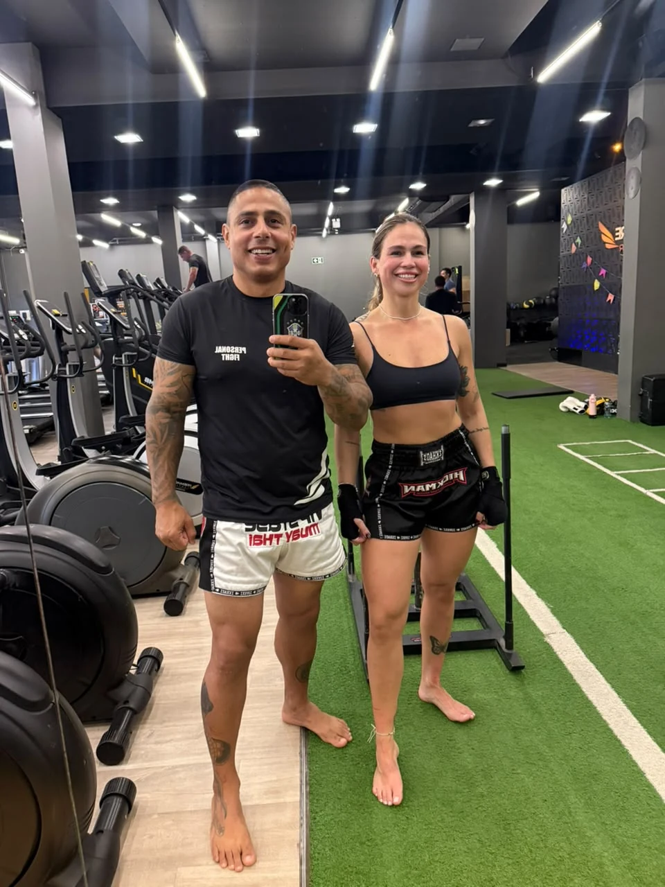 Anderson Hickman ao lado de aluna na sala de musculação