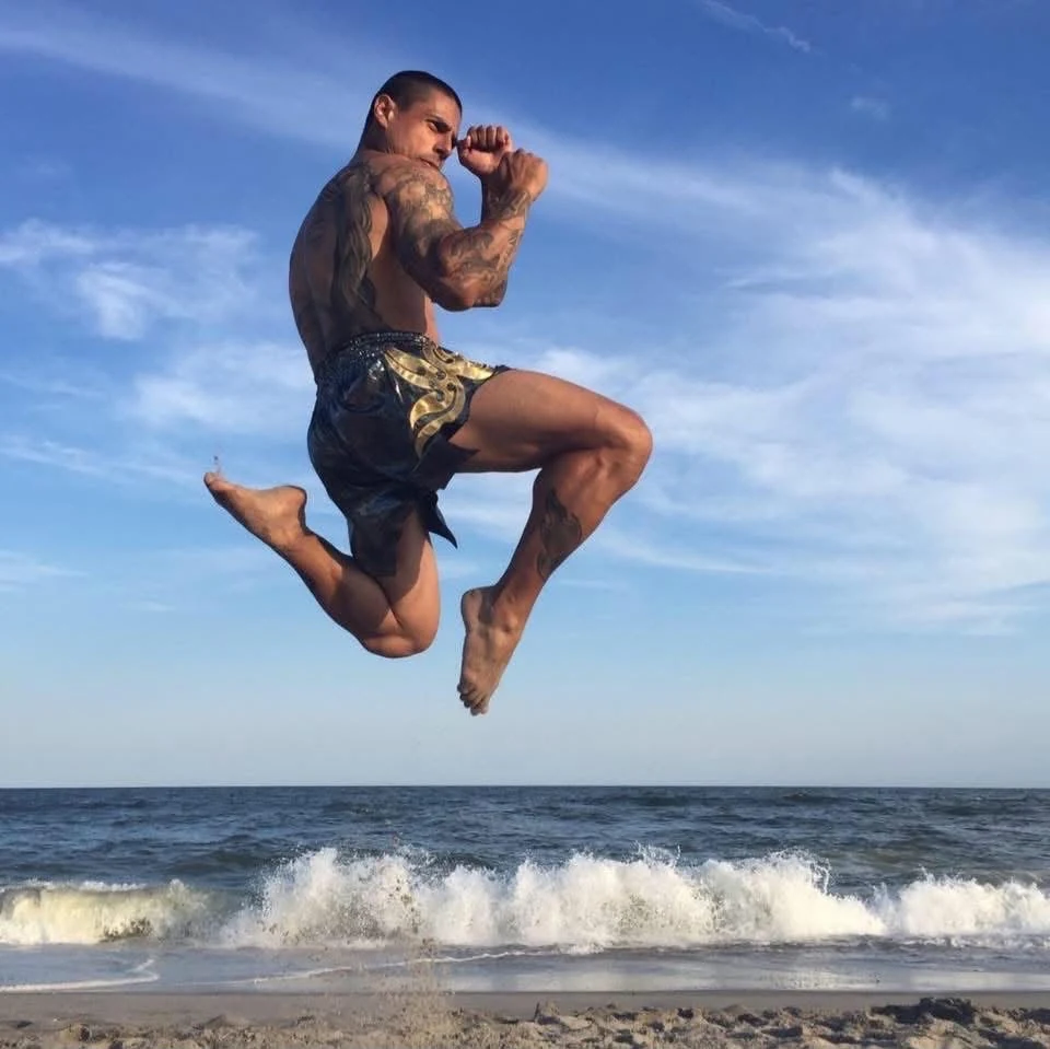 Anderson Hickman executando um chute voador durante treino na praia